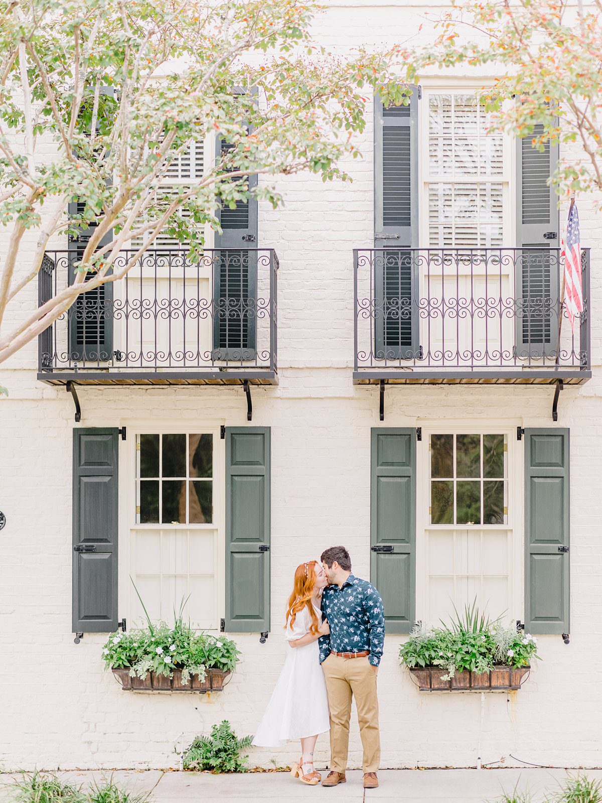 couple kissing in front of old white house in downtown charleston