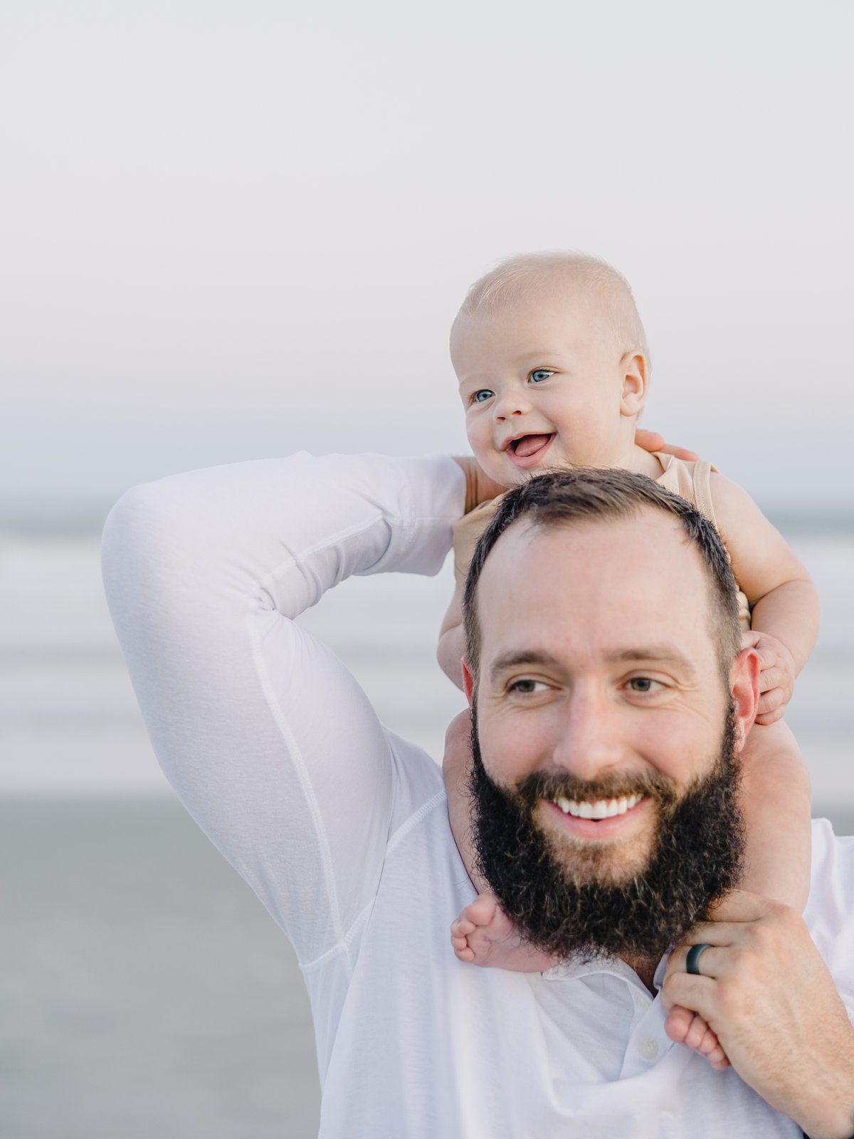 baby on dad's shoulders at the beach