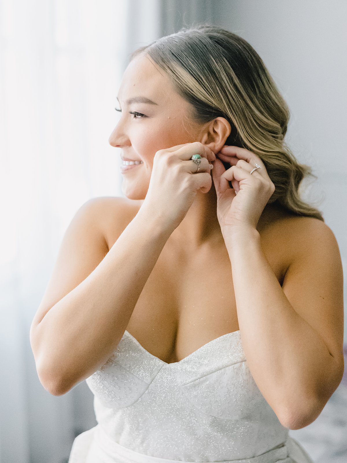 bride putting in earrings as she gets ready