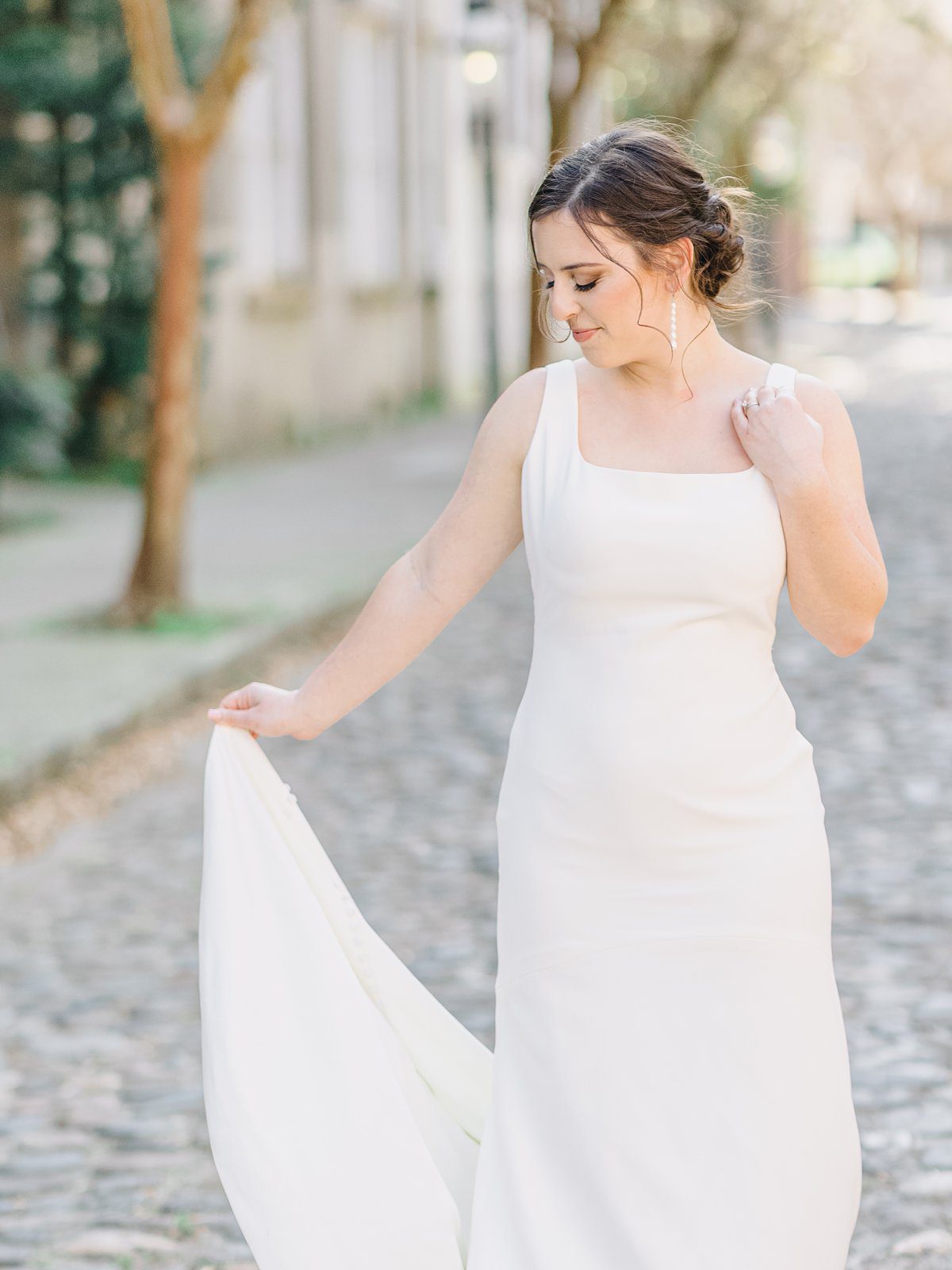 bride in simple white gown admires her dress in downtown Charleston