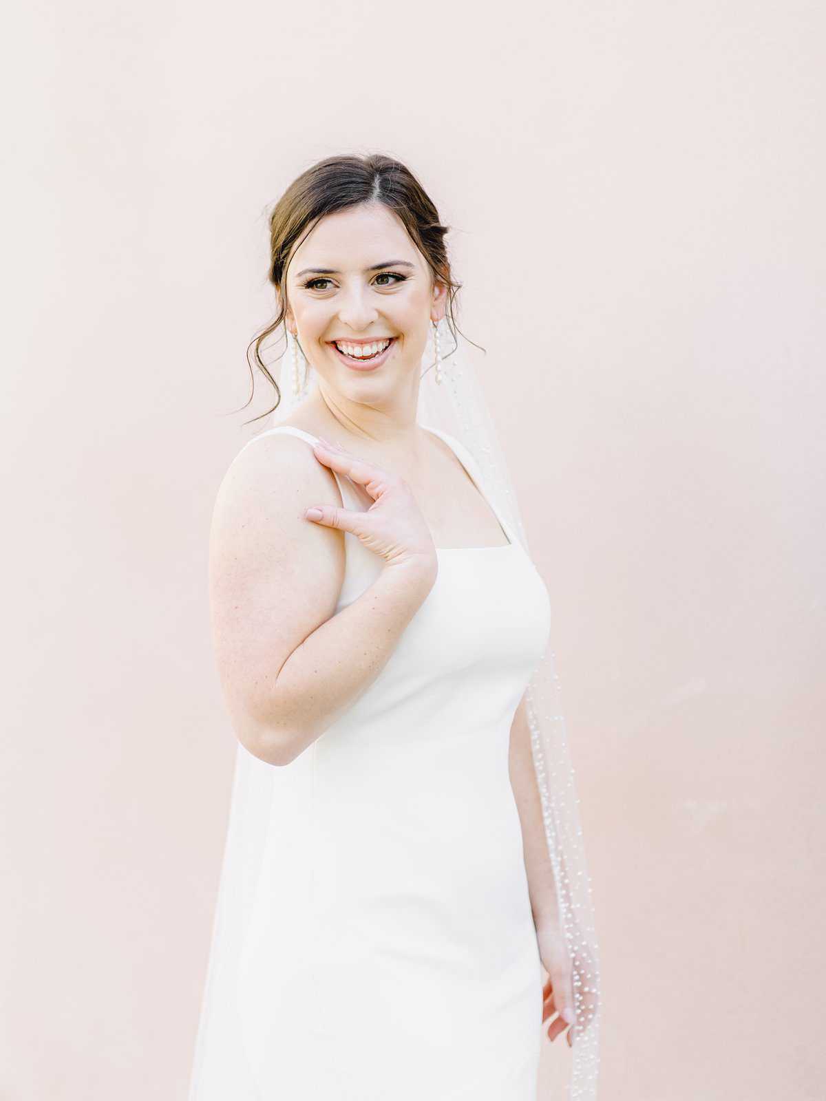 bride in simple white gown laughs over her shoulder in downtown Charleston at her bridal session