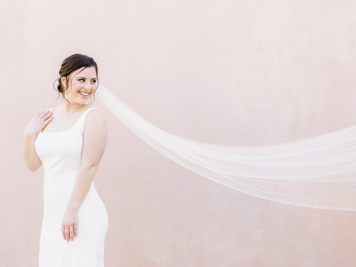 bride in simple white gown with long flowing veil in downtown Charleston at her bridal session