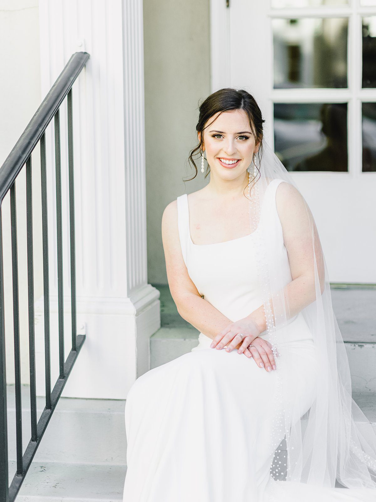 bride in simple white gown sitting on steps in downtown Charleston