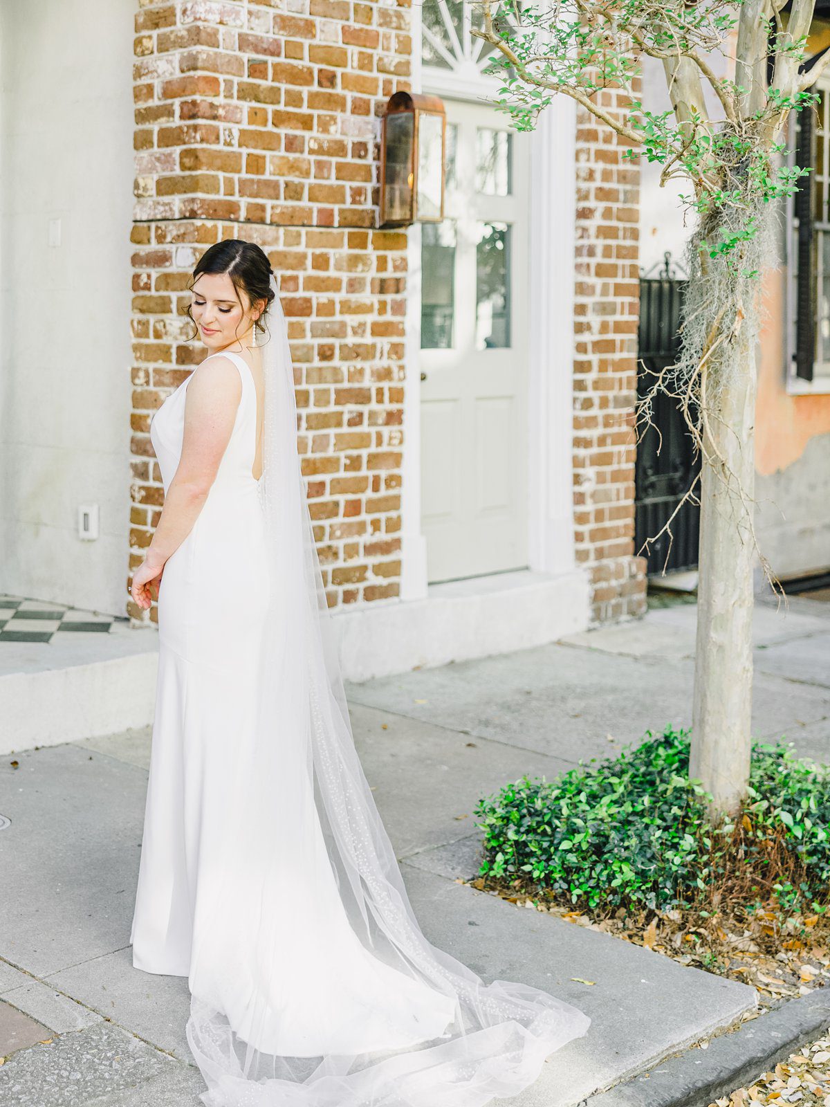 bride in simple white gown in downtown Charleston at her bridal session
