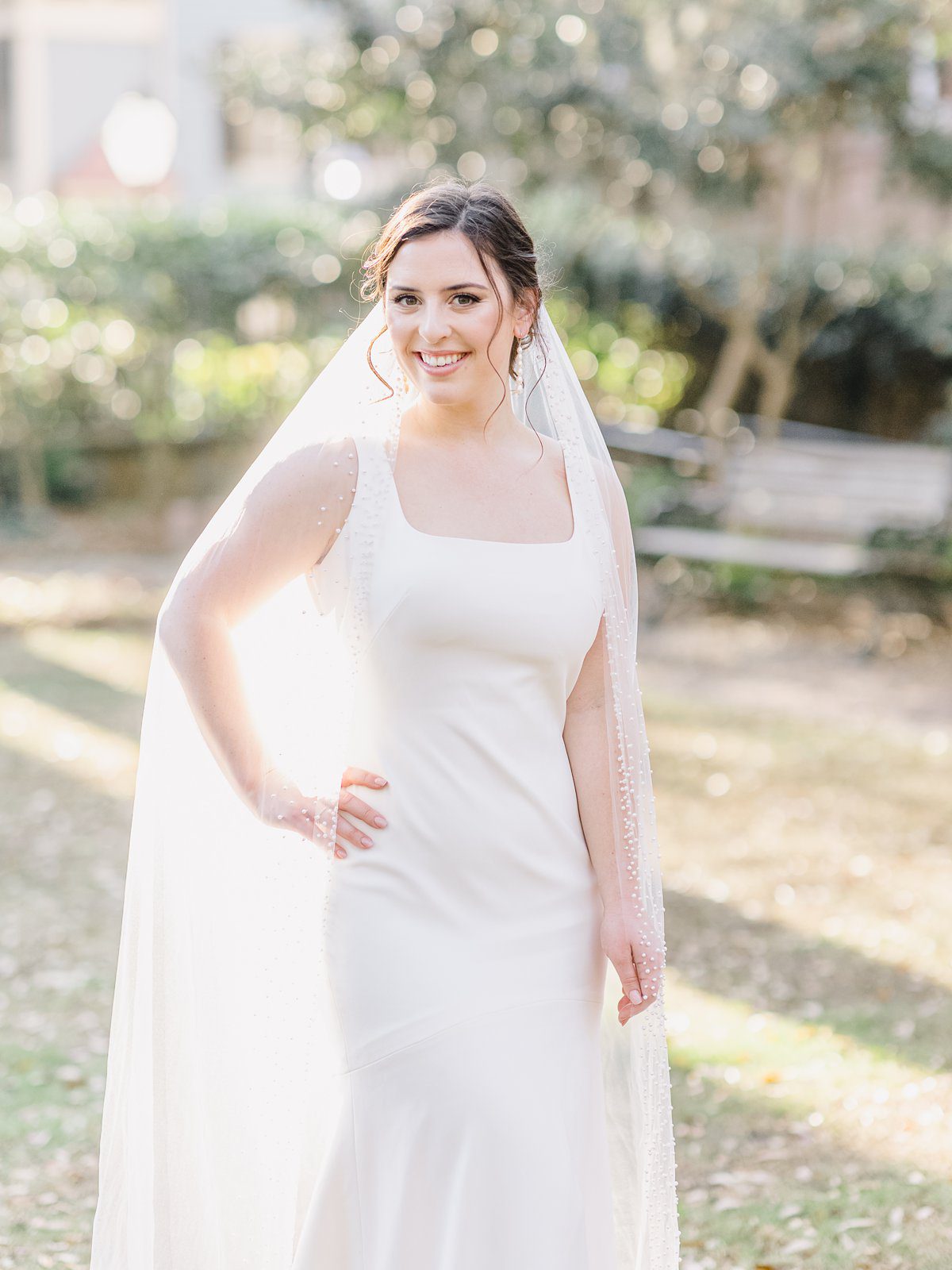 bride in simple white gown and long beaded veil in downtown Charleston at her bridal session