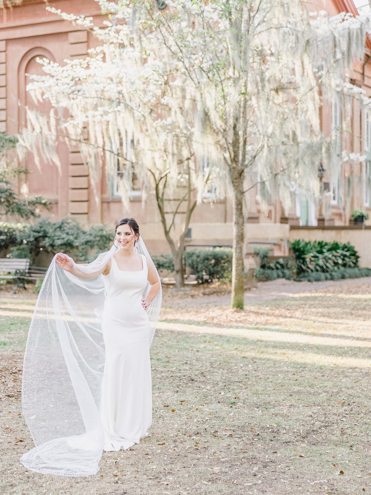 bride plays with her veil in downtown Charleston at her bridal session
