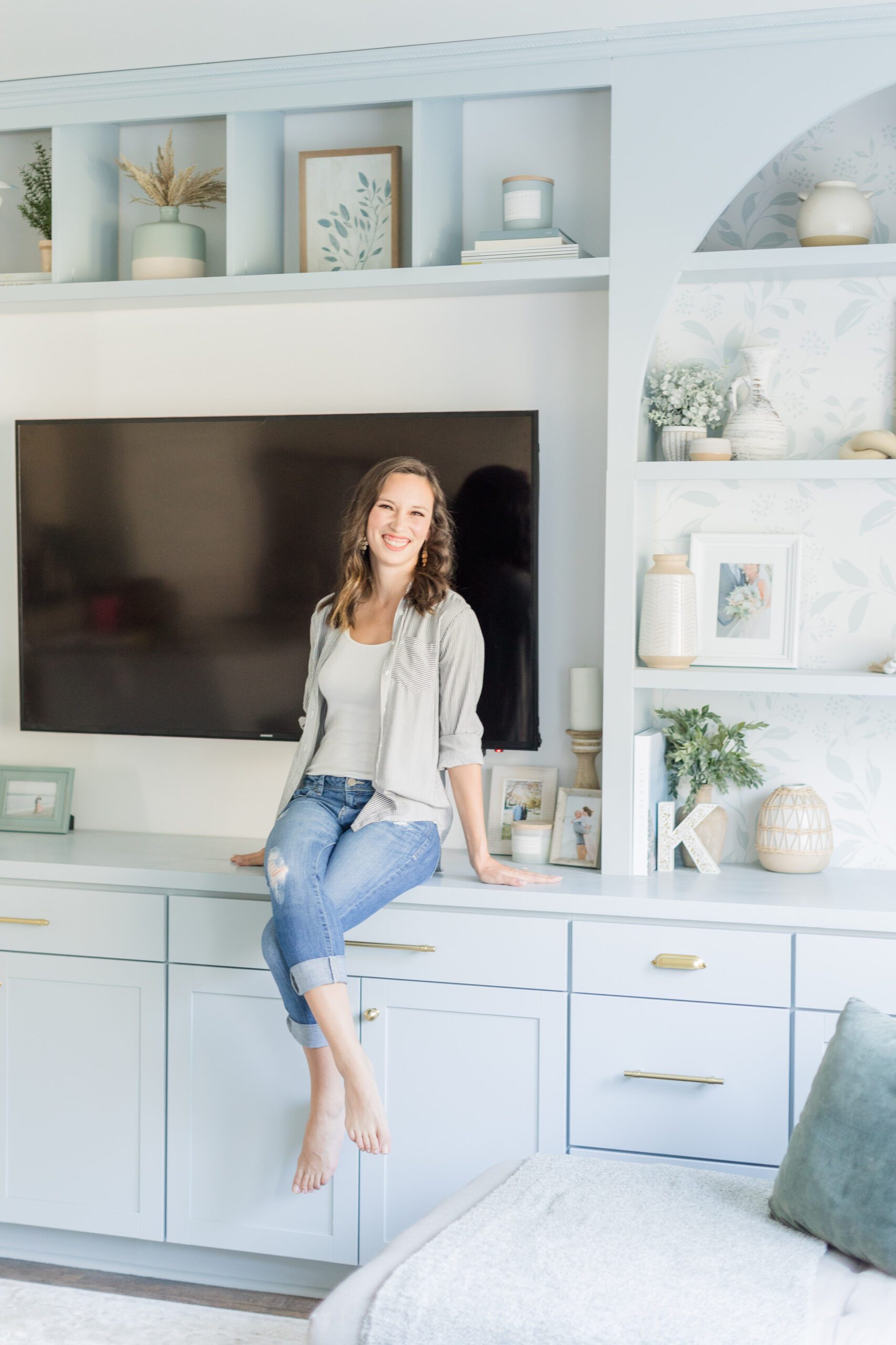 girl sits on the counter of her blue built-ins in the living room