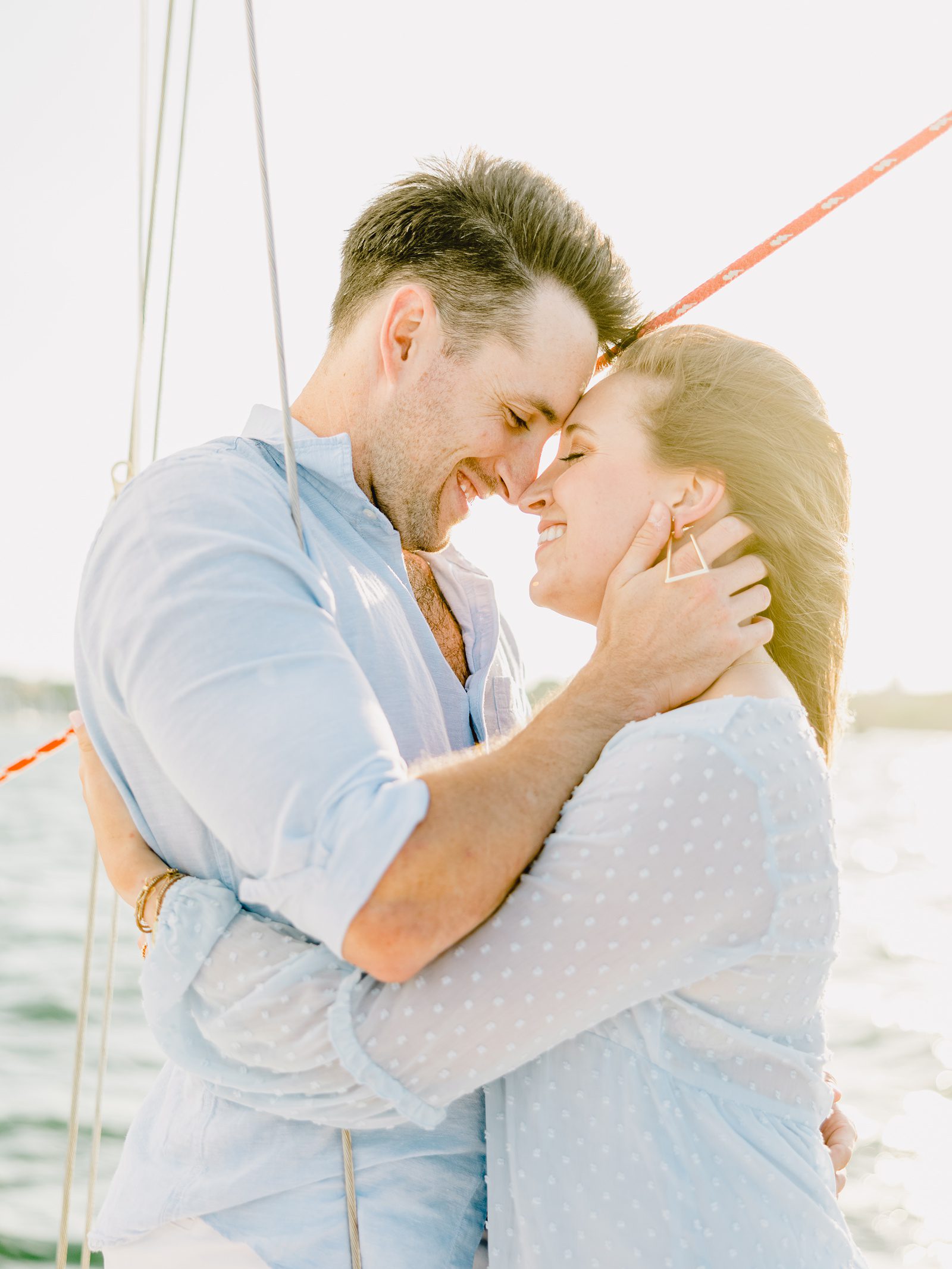 engaged couple on a sailboat at sunset