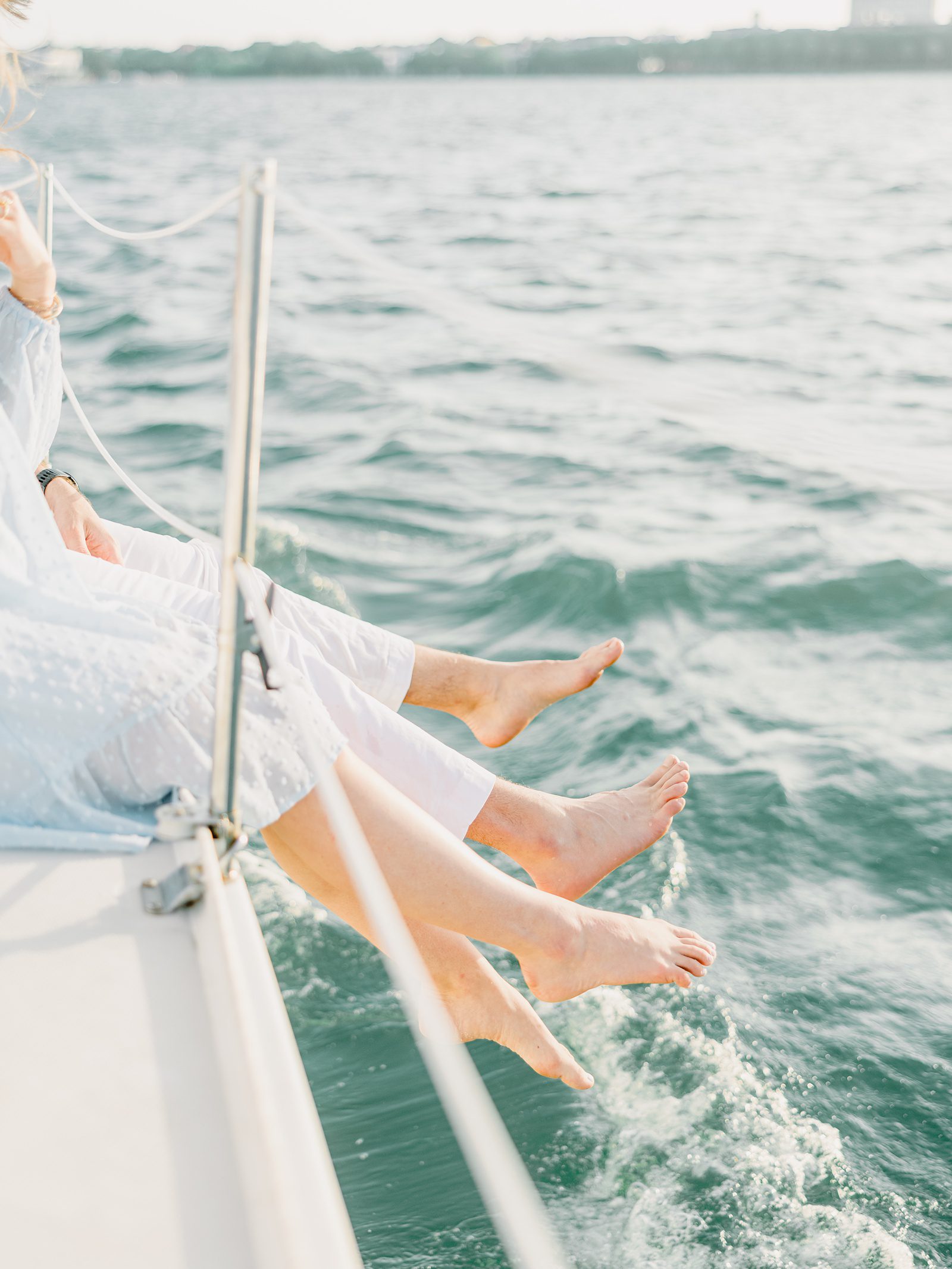 couple splashing their feet off the side of a sailboat