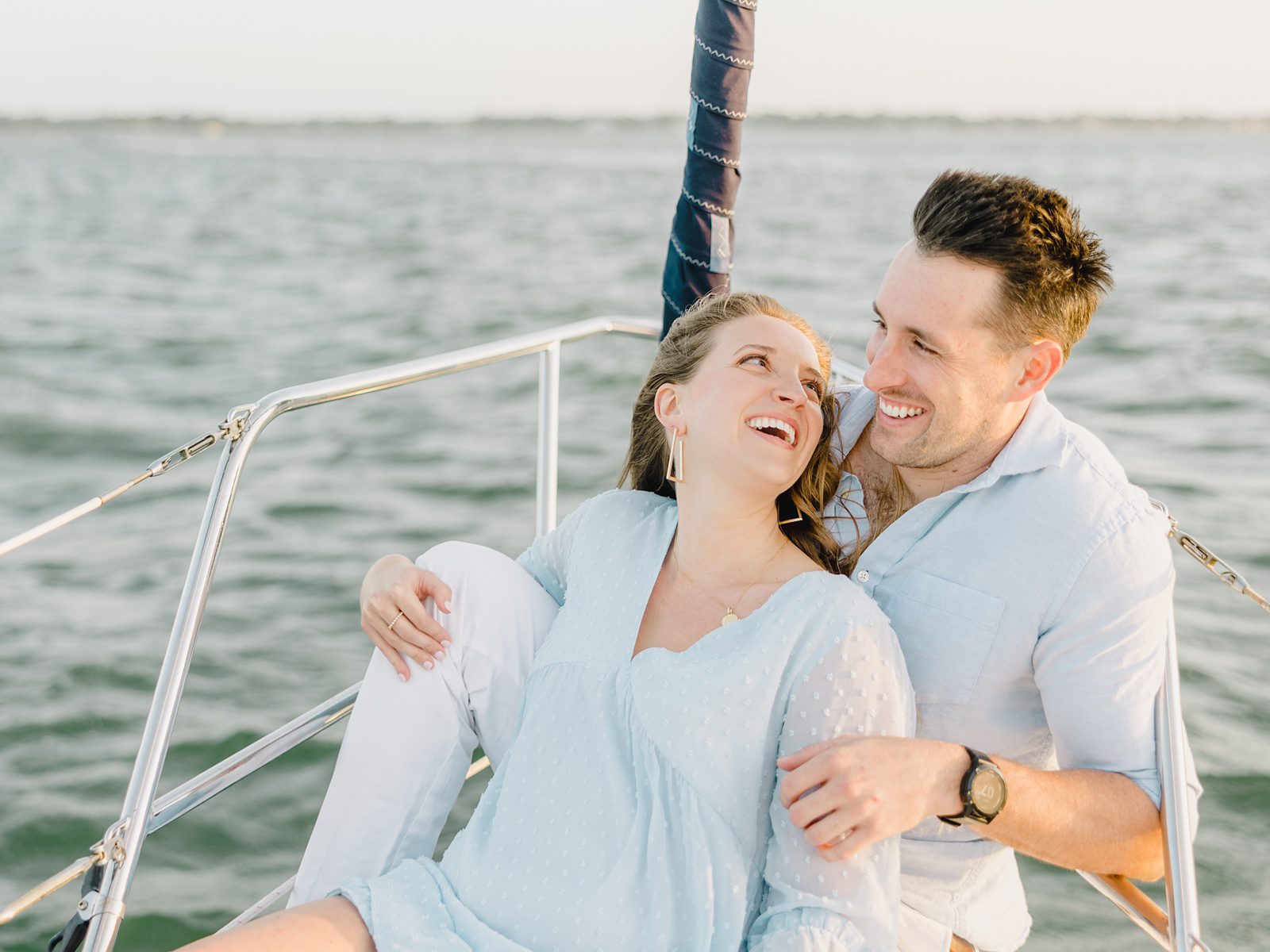 couple laughing at their engagement session on a sailboat