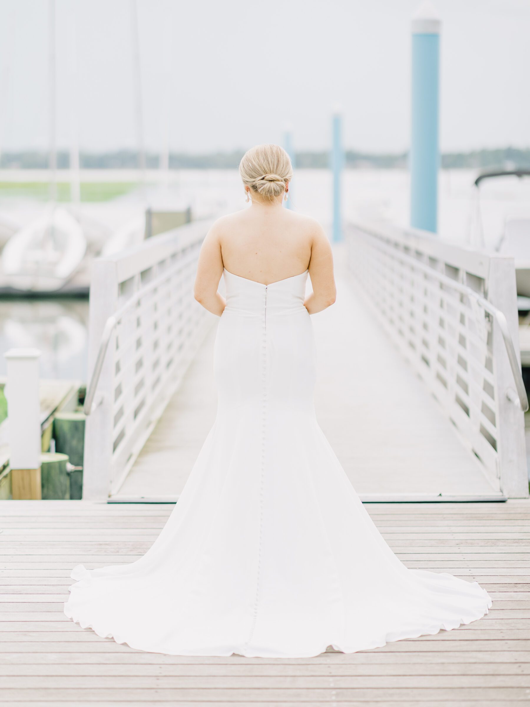 A bride in a long, white wedding gown with buttons down the back at her Citadel docks bridal session