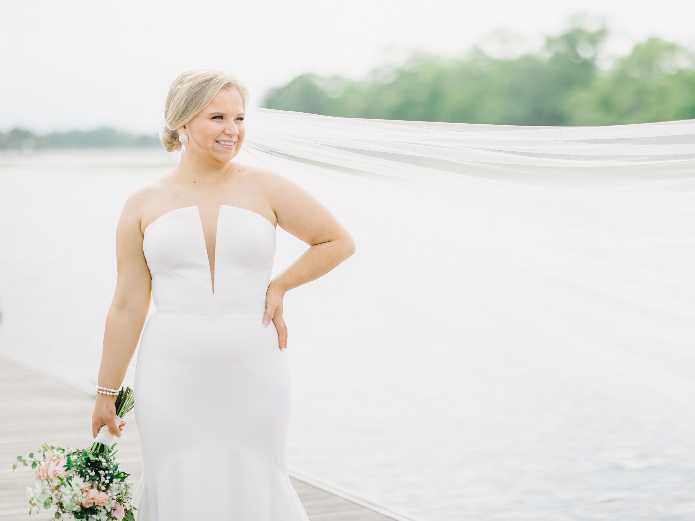 A bride smiles into the distance with a long flowy veil at her Citadel docks bridal session