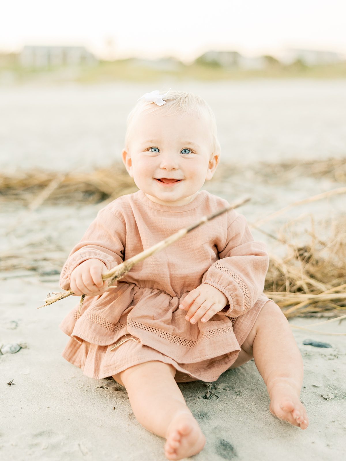little girl in pink dress smiling at beach family session