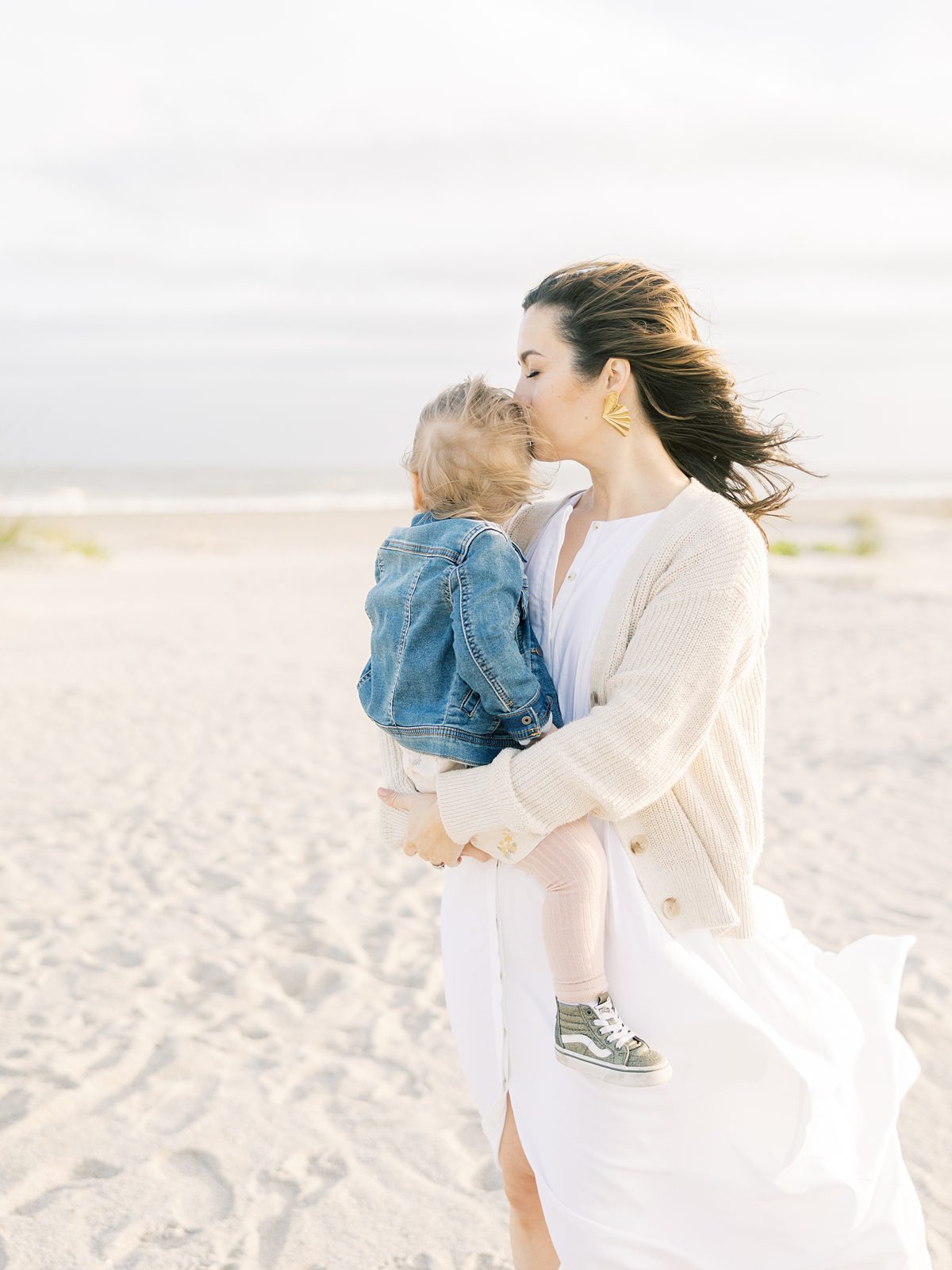 mother snuggles daughter on a cold windy beach day