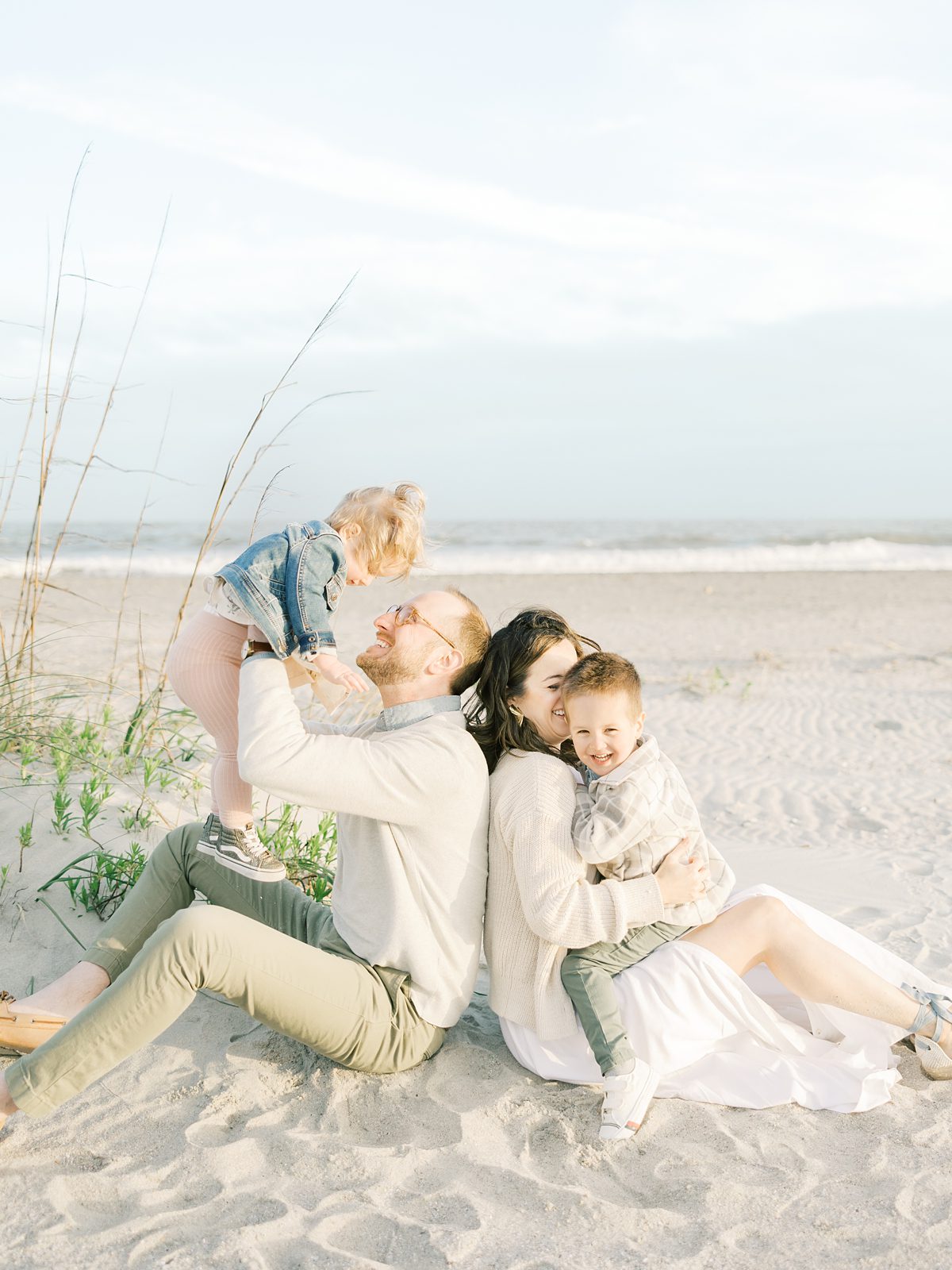 parents play with their children sitting in the sand at the beach