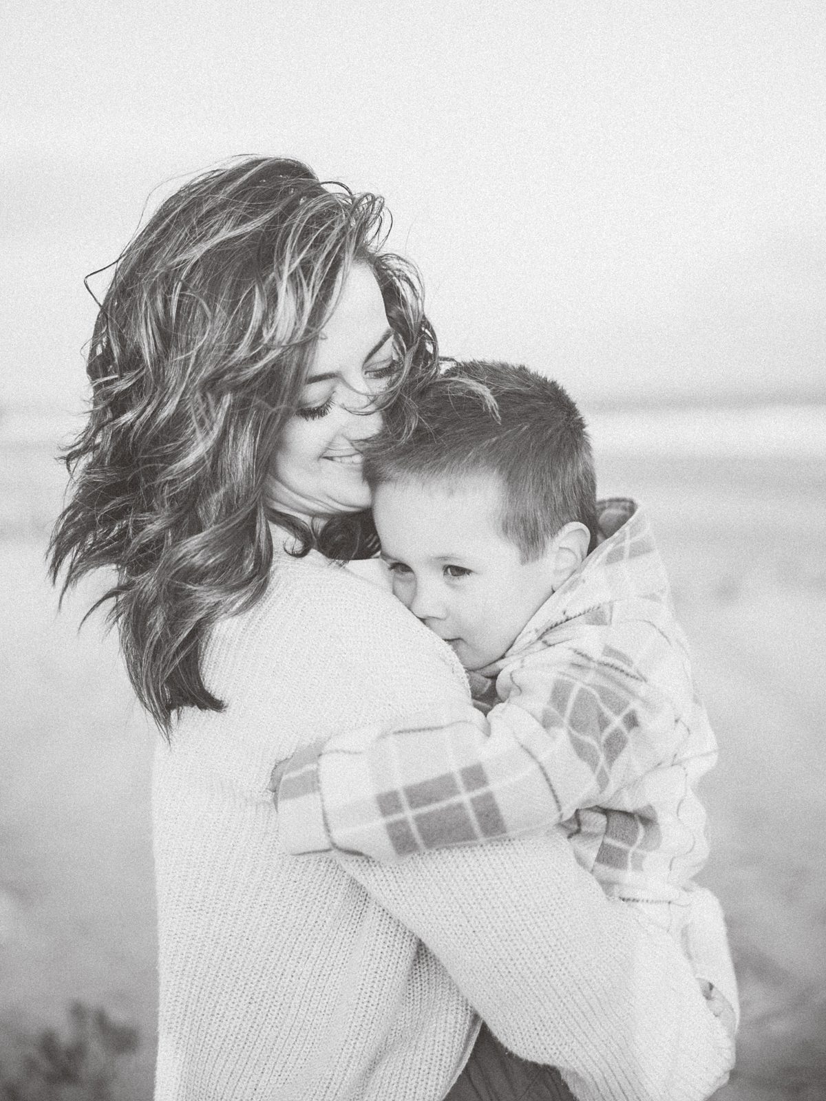 mom snuggles son on a cold windy day. Black and white image