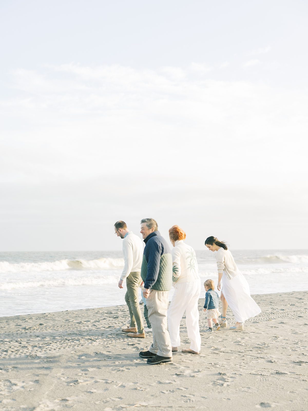 family walks along the ocean at the beach on a sunny evening