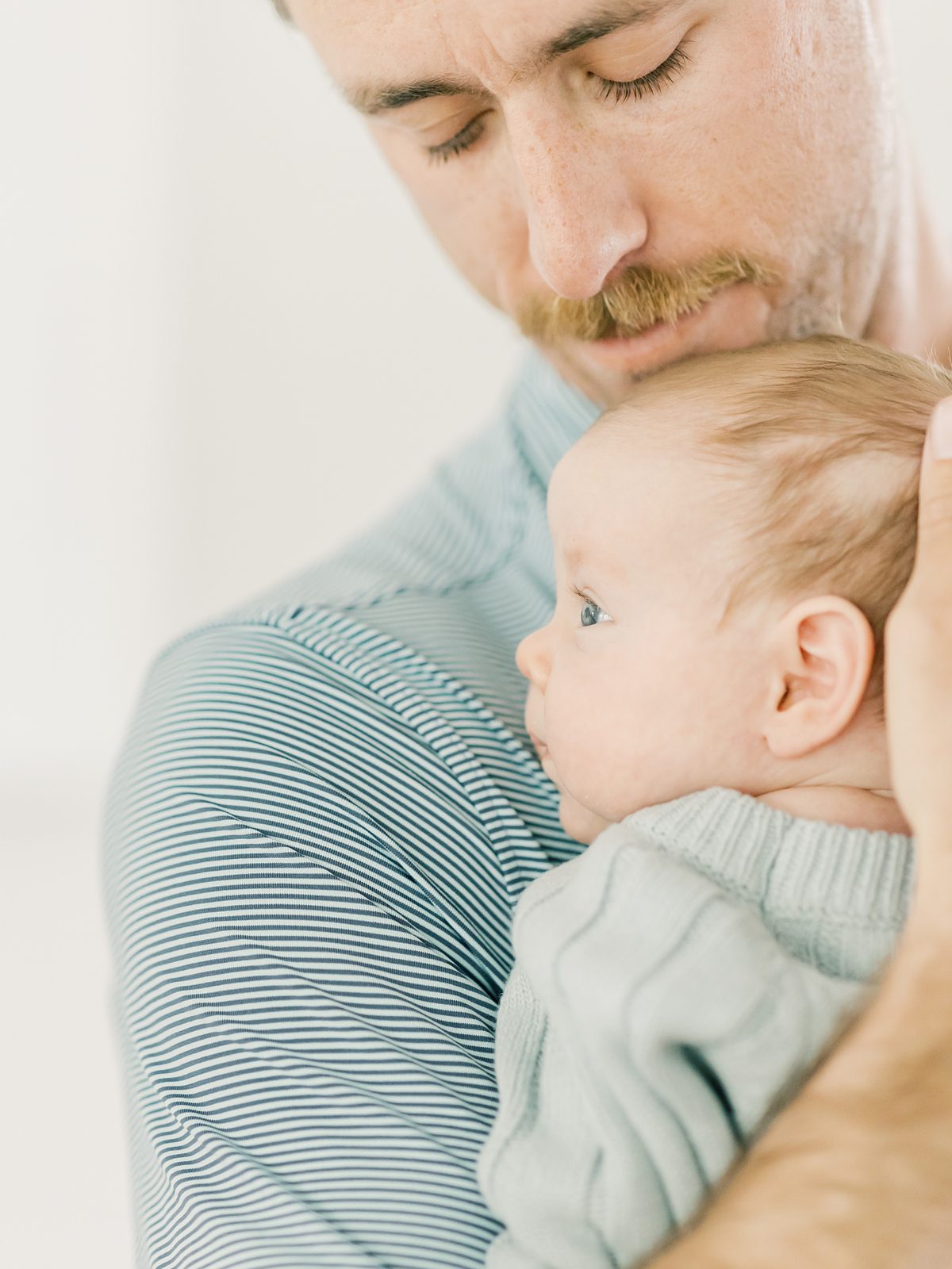 dad snuggles newborn baby girl at their in-home newborn session