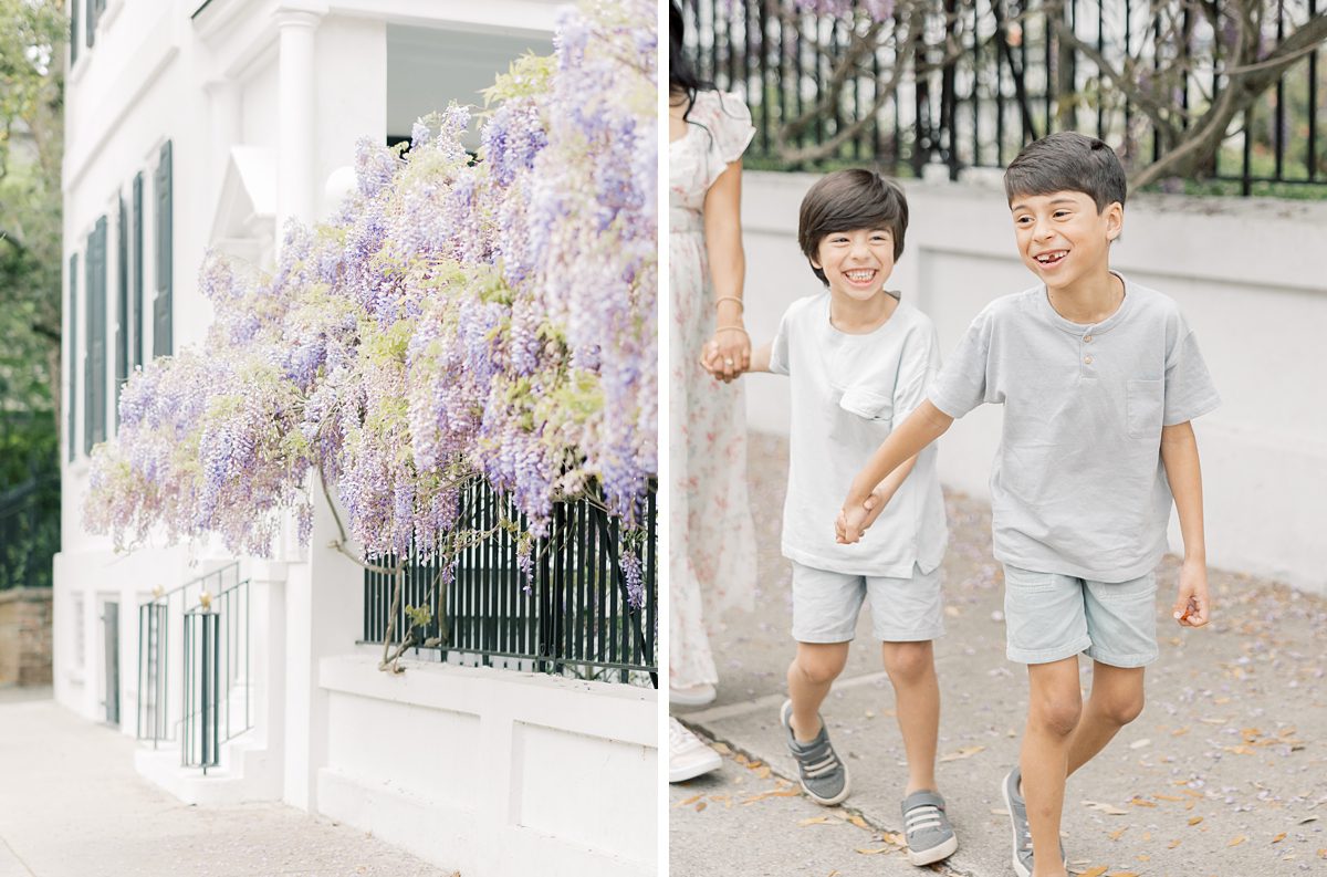 little boys hold hands laughing and walking next to wisteria vines